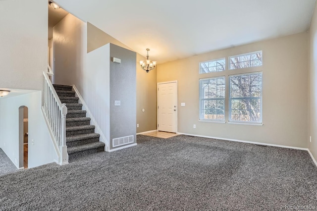 carpeted foyer entrance featuring a notable chandelier