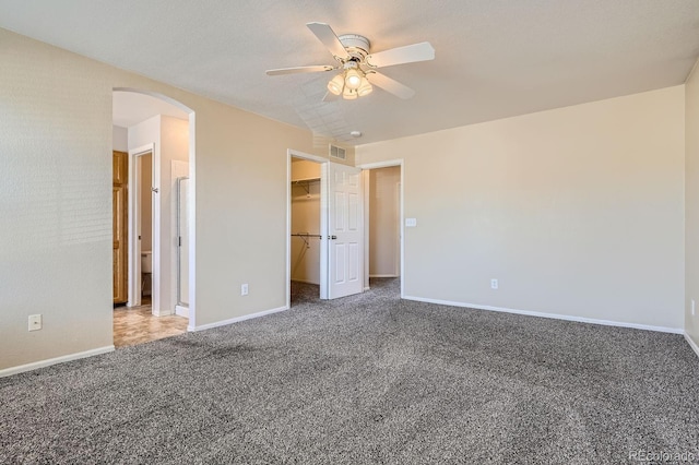 unfurnished bedroom featuring a spacious closet, a closet, ceiling fan, and carpet flooring