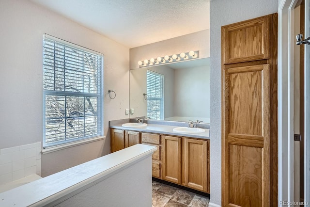 bathroom featuring a healthy amount of sunlight, vanity, and a textured ceiling