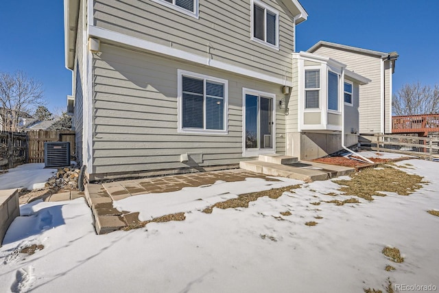 snow covered house featuring central AC unit