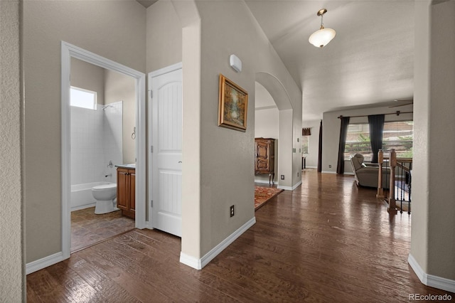 15616 Soo Line Way, Monument, CO 80132 - hallway featuring arched walkways, dark wood-style floors, and baseboards