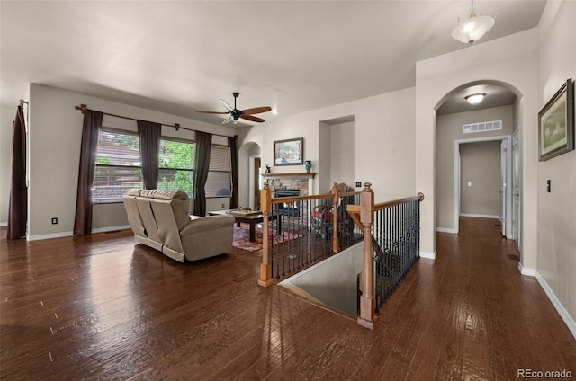 15616 Soo Line Way, Monument, CO 80132 - living room with arched walkways, a ceiling fan, wood finished floors, baseboards, and a stone fireplace