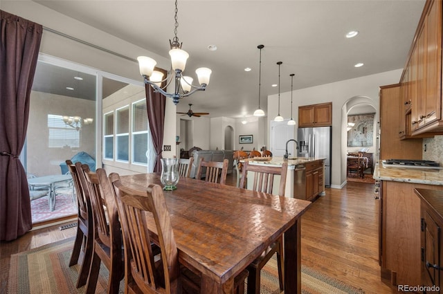 15616 Soo Line Way, Monument, CO 80132 - dining room featuring a chandelier, arched walkways, a ceiling fan, dark wood-style flooring, and recessed lighting