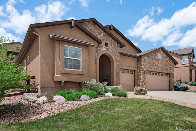 15616 Soo Line Way, Monument, CO 80132 - view of front of property featuring a garage, driveway, stone siding, a front lawn, and stucco siding