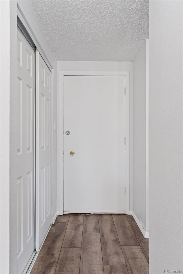 doorway featuring a textured ceiling, baseboards, and wood finished floors