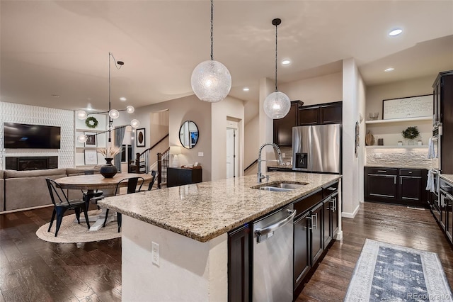 kitchen featuring hanging light fixtures, sink, an island with sink, dark hardwood / wood-style flooring, and stainless steel appliances