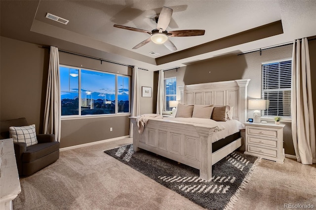 bedroom featuring ceiling fan, a raised ceiling, light colored carpet, and a textured ceiling