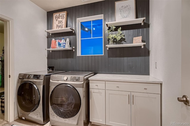 laundry area with separate washer and dryer, wood walls, and cabinets