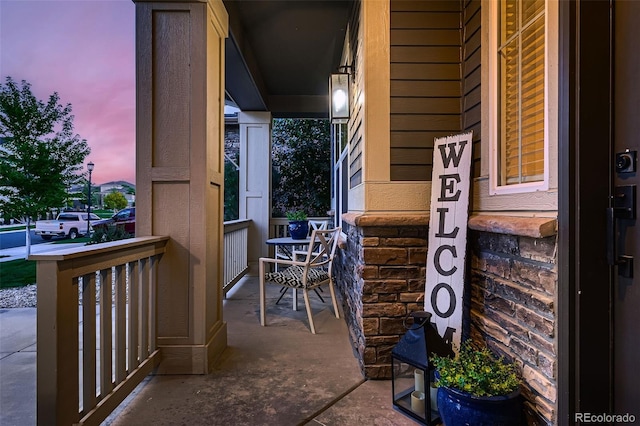 balcony at dusk featuring a porch