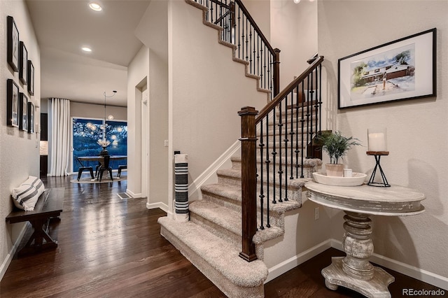 stairs with wood-type flooring and an inviting chandelier