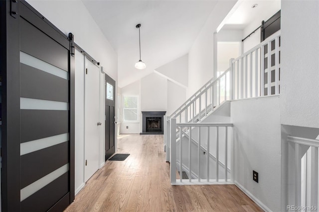 772 Ivywood Ct, Highlands Ranch, CO 80126 - entrance foyer with a barn door, light wood-style floors, high vaulted ceiling, a fireplace with raised hearth, and baseboards