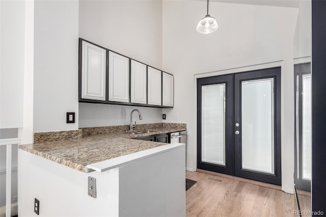772 Ivywood Ct, Highlands Ranch, CO 80126 - kitchen featuring a sink, french doors, light wood-style flooring, a peninsula, and decorative light fixtures