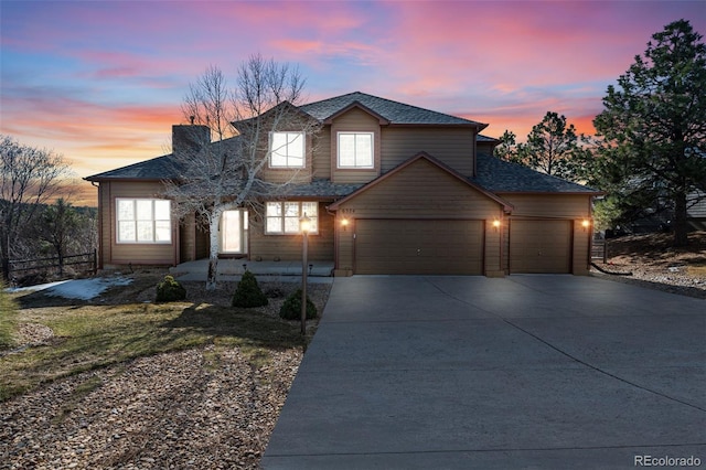 traditional home with a garage, roof with shingles, and concrete driveway