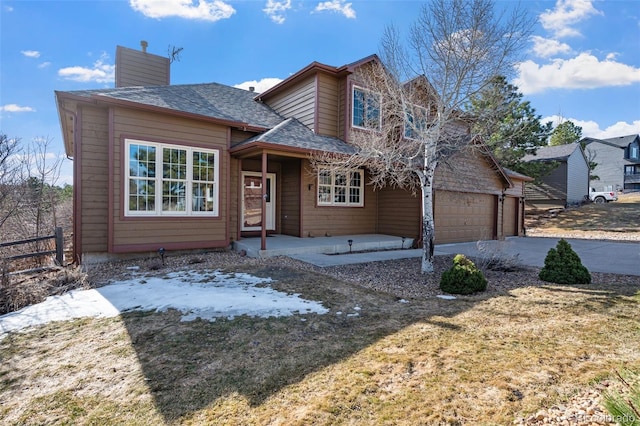 view of front facade with a chimney, a garage, driveway, and roof with shingles