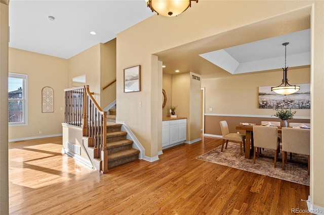 dining area featuring visible vents, baseboards, wood finished floors, and stairs