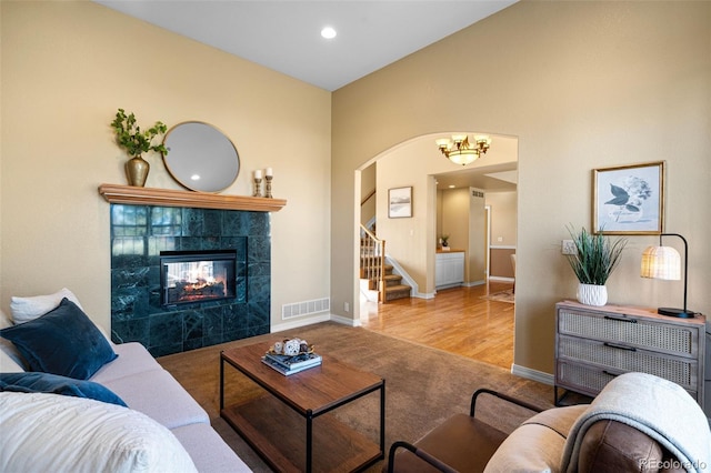 carpeted living room with stairway, baseboards, visible vents, lofted ceiling, and a tile fireplace