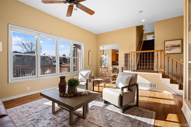 living room featuring stairs, wood finished floors, visible vents, and baseboards