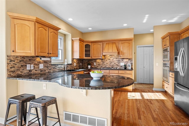 kitchen with visible vents, a breakfast bar, appliances with stainless steel finishes, a peninsula, and custom exhaust hood