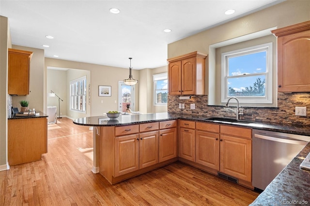 kitchen featuring visible vents, a peninsula, a sink, light wood-style floors, and stainless steel dishwasher