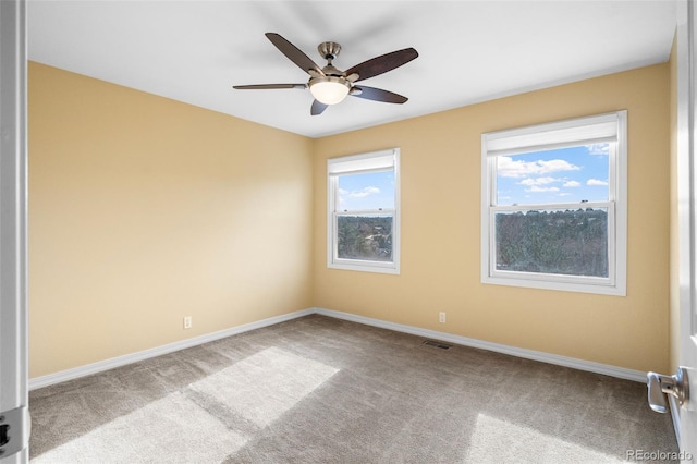 carpeted spare room featuring visible vents, a ceiling fan, and baseboards