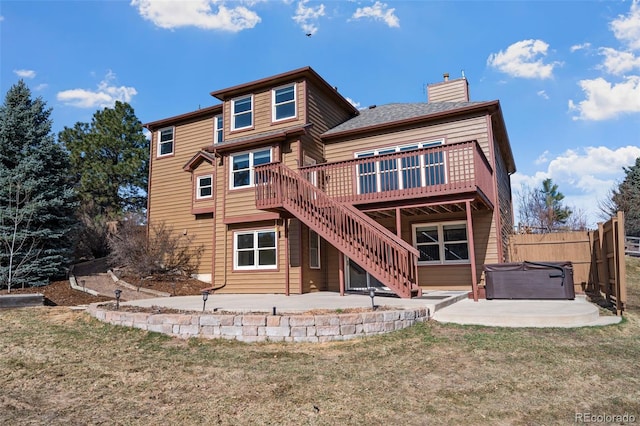 back of house featuring a hot tub, fence, a wooden deck, a yard, and a patio area