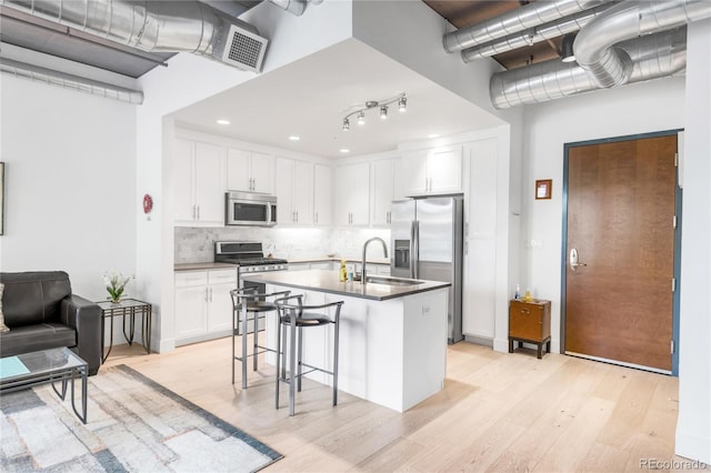 3401 Arapahoe Ave Unit 105, Boulder, CO 80303 - kitchen with appliances with stainless steel finishes, a sink, a breakfast bar, light wood finished floors, and tasteful backsplash