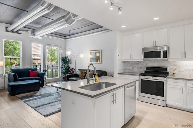 3401 Arapahoe Ave Unit 105, Boulder, CO 80303 - kitchen featuring appliances with stainless steel finishes, a sink, open floor plan, light wood-style floors, and white cabinets