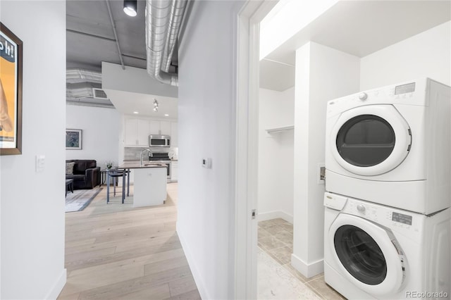 3401 Arapahoe Ave Unit 105, Boulder, CO 80303 - laundry room with stacked washer and clothes dryer, light wood-style floors, and baseboards