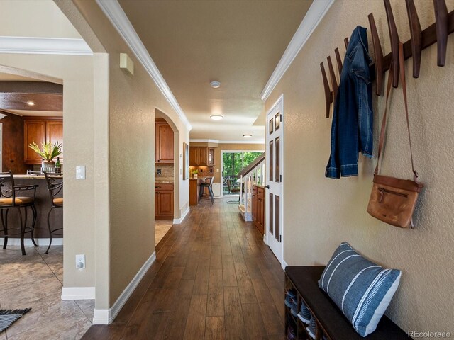 10954 W 100th Way, Broomfield, CO 80021 - hallway featuring arched walkways, ornamental molding, a textured wall, and dark wood-style flooring