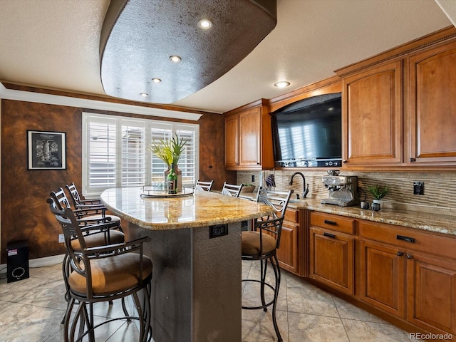 10954 W 100th Way, Broomfield, CO 80021 - kitchen featuring a breakfast bar area, tasteful backsplash, light stone counters, recessed lighting, and a textured ceiling