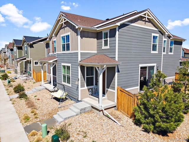 view of front of home with a residential view, roof with shingles, board and batten siding, and fence