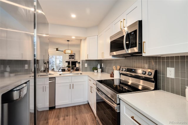 kitchen with sink, hanging light fixtures, light hardwood / wood-style flooring, white cabinets, and appliances with stainless steel finishes