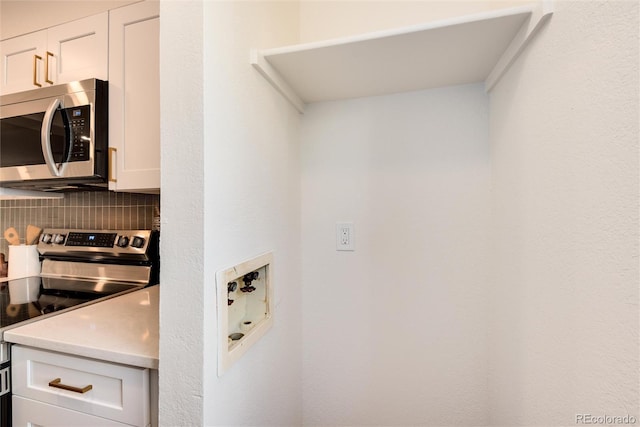 kitchen featuring tasteful backsplash, white cabinetry, and appliances with stainless steel finishes