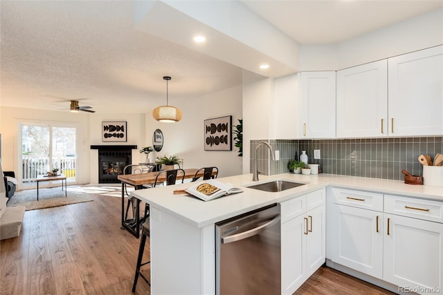 kitchen with kitchen peninsula, white cabinetry, stainless steel dishwasher, and sink