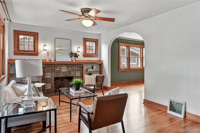 3611 N Vine St, Denver, CO 80205 - living area featuring baseboards, crown molding, a brick fireplace, arched walkways, and a ceiling fan
