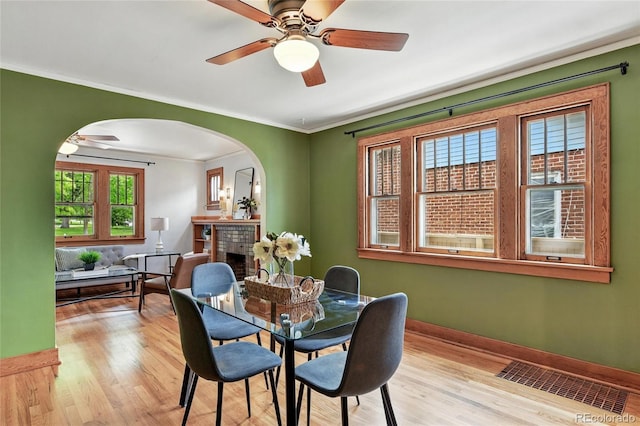 3611 N Vine St, Denver, CO 80205 - dining room with arched walkways, light wood-type flooring, ornamental molding, a brick fireplace, and a ceiling fan