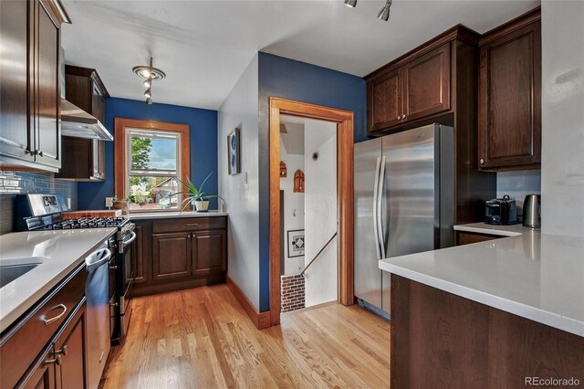 3611 N Vine St, Denver, CO 80205 - kitchen with appliances with stainless steel finishes, wall chimney exhaust hood, light wood-style floors, light countertops, and dark brown cabinetry