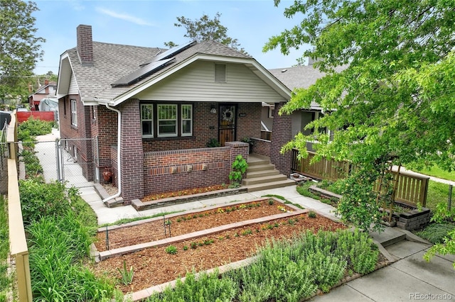 3611 N Vine St, Denver, CO 80205 - view of front of property with brick siding, solar panels, a chimney, a shingled roof, and a gate