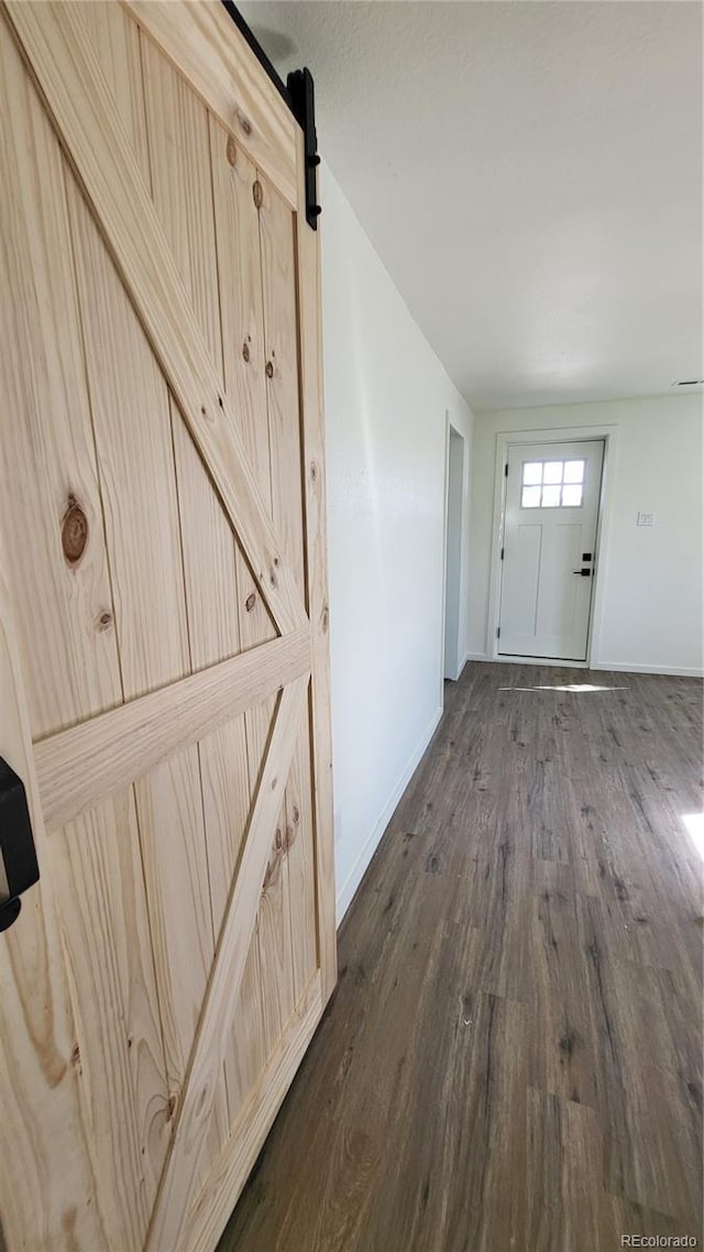 corridor featuring a barn door and dark wood-type flooring