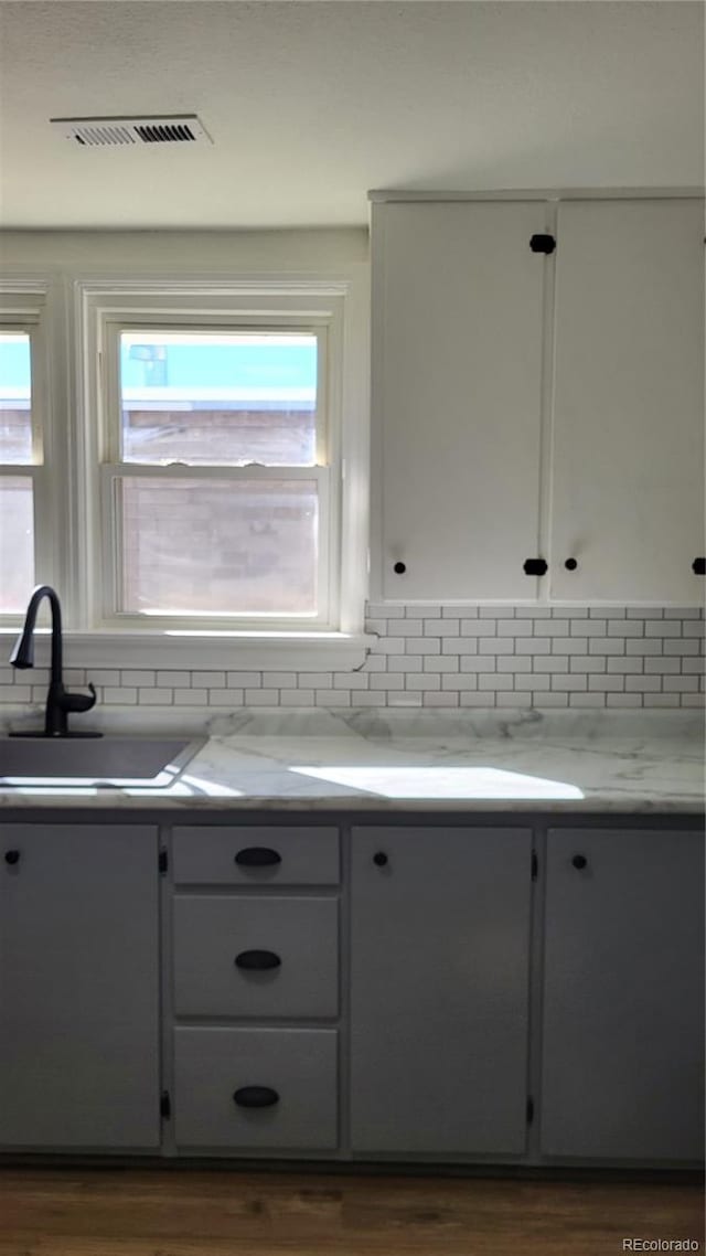 kitchen with dark hardwood / wood-style floors, light stone counters, sink, and tasteful backsplash