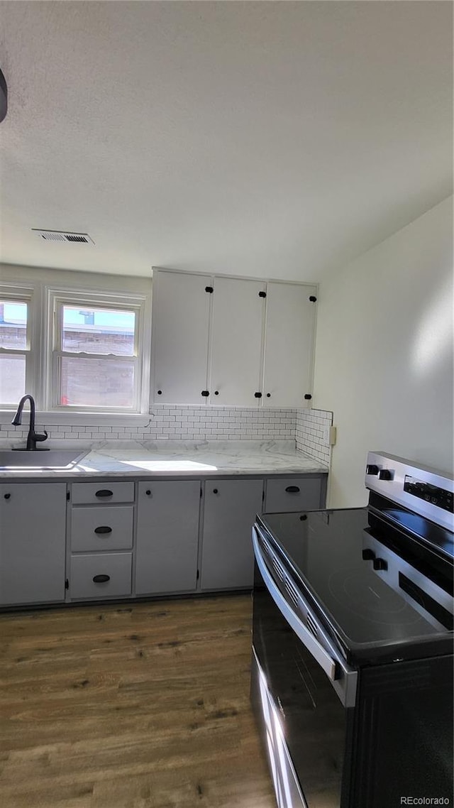 kitchen featuring backsplash, stainless steel range with electric stovetop, dark wood-type flooring, and sink