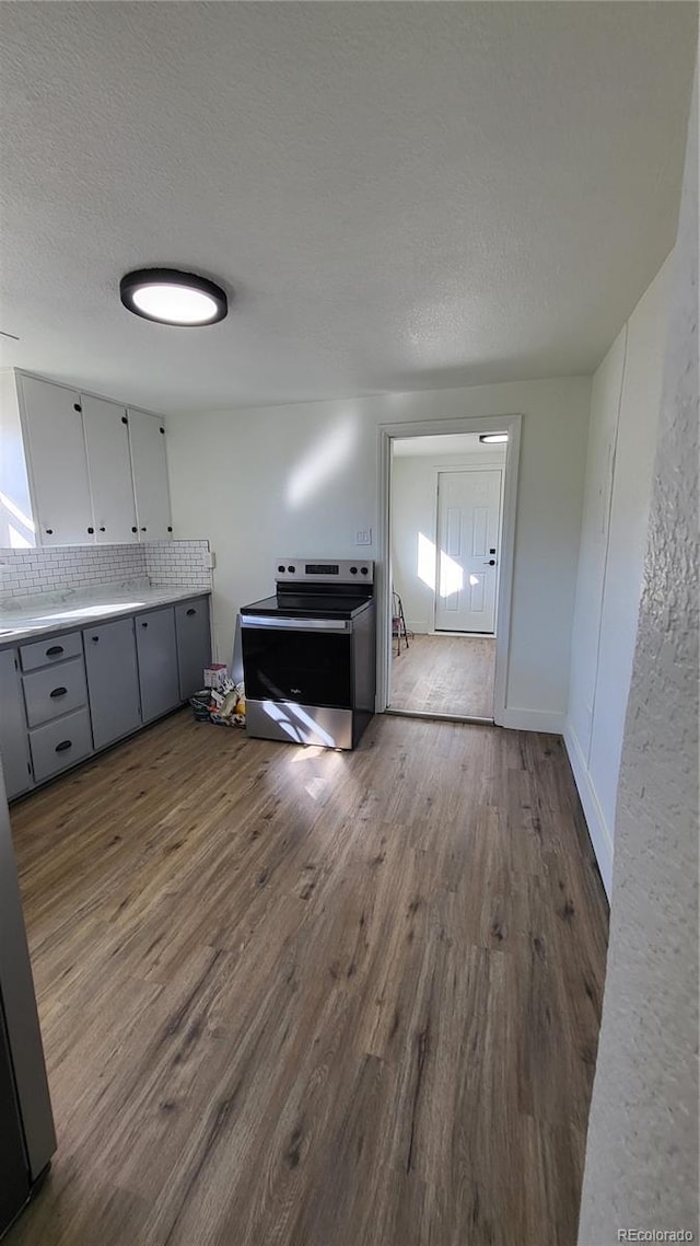 interior space featuring hardwood / wood-style flooring, decorative backsplash, and a textured ceiling