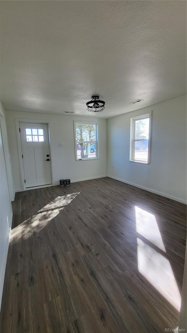 unfurnished living room featuring dark hardwood / wood-style floors, plenty of natural light, and a textured ceiling