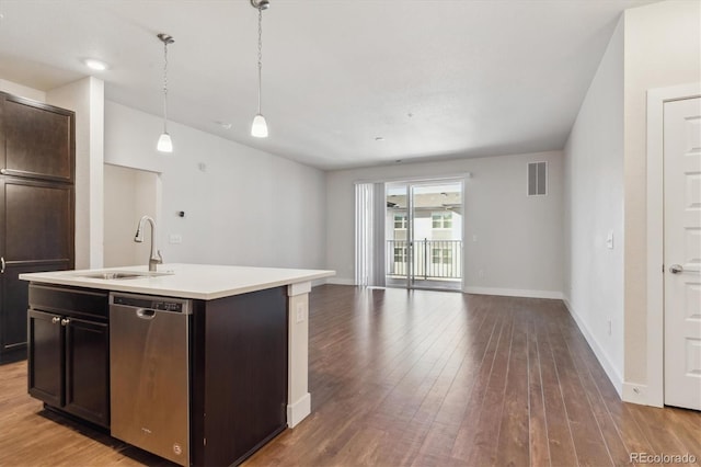 kitchen with a center island with sink, dark wood-type flooring, hanging light fixtures, stainless steel dishwasher, and sink