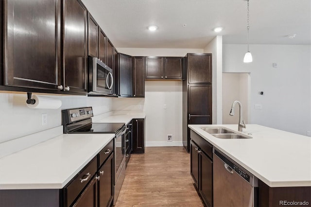 kitchen featuring light hardwood / wood-style floors, appliances with stainless steel finishes, pendant lighting, dark brown cabinetry, and sink