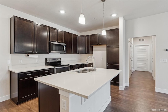 kitchen with decorative light fixtures, sink, appliances with stainless steel finishes, and an island with sink