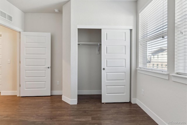 unfurnished bedroom featuring dark wood-type flooring and a closet