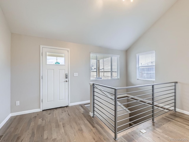 foyer with a healthy amount of sunlight, wood-type flooring, and lofted ceiling