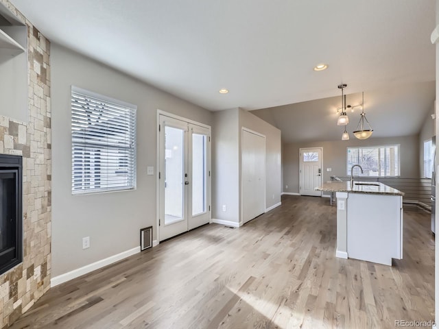 kitchen featuring a breakfast bar, french doors, sink, a fireplace, and decorative light fixtures