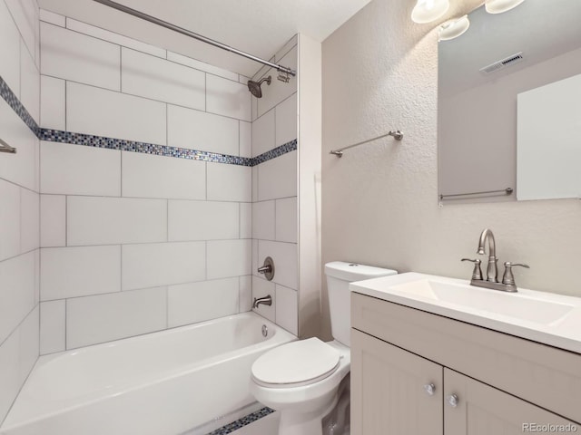 full bathroom featuring vanity, tiled shower / bath, and toilet